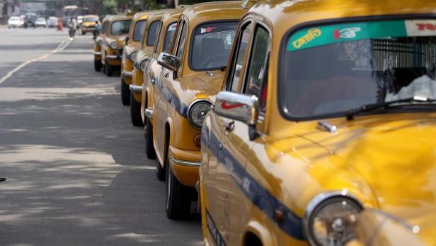 Eine Reihe gelber Taxis steht auf einer Straße.