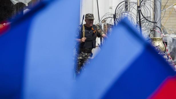 Ein Mann in Militärkleidung steht vor einem Stacheldrahtzaun.