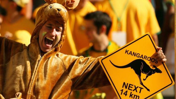 Ein Mann im Känguru-Kostüm hält ein Verkehrsschild mit der Aufschrift „Kängurus nächste 14 km“.