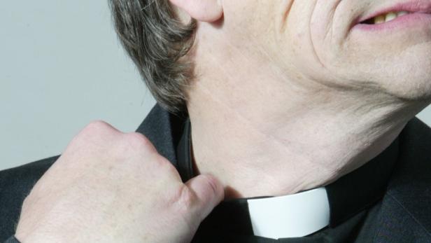Ein Mann im Priesterkragen lockert seinen Kragen.