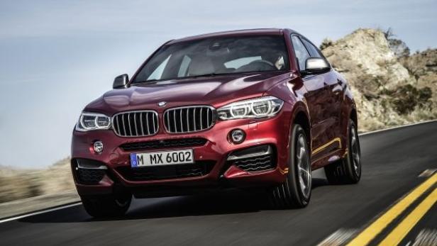Ein roter BMW X6 fährt auf einer asphaltierten Straße.