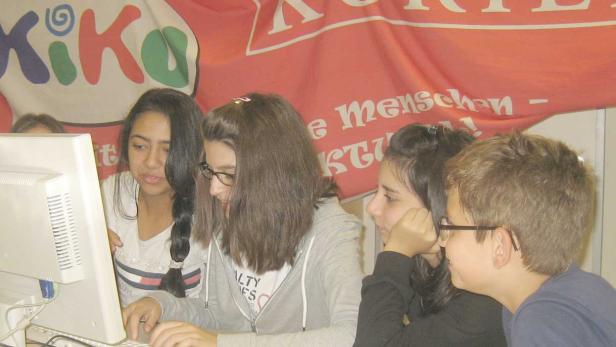 Eine Gruppe von Jugendlichen sitzt vor einem Computer.