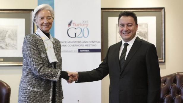 Christine Lagarde schüttelt einem Mann die Hand vor einem G20-Banner.