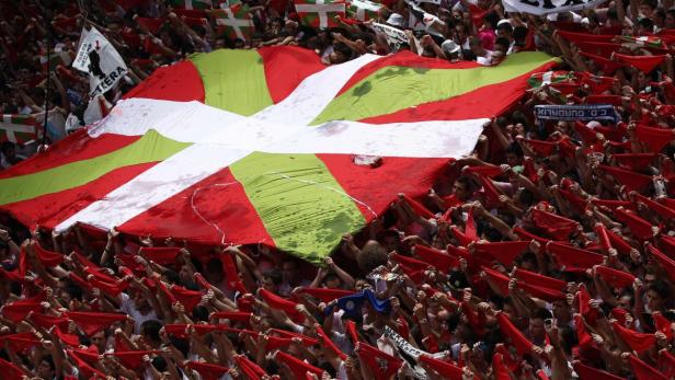 Eine Menschenmenge hält eine riesige Ikurriña, die Flagge des Baskenlandes, hoch.