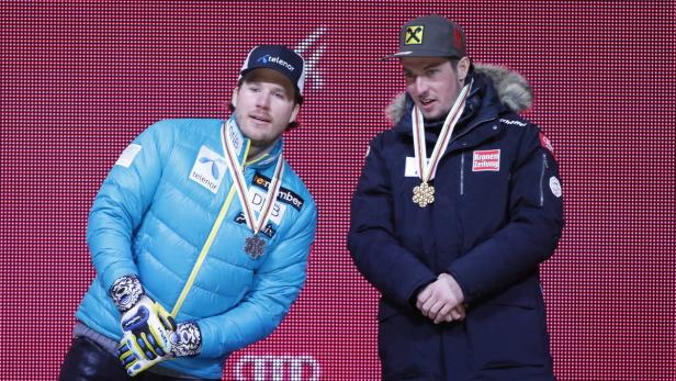 Zwei Skirennläufer stehen mit Medaillen vor einer roten Wand.
