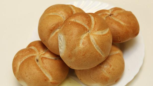 Fünf Kaisersemmeln liegen auf einem weißen Teller.