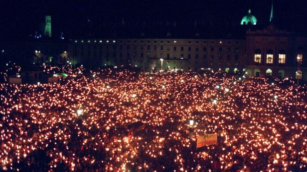Eine große Menschenmenge hält bei Nacht leuchtende Kerzen in der Hand.