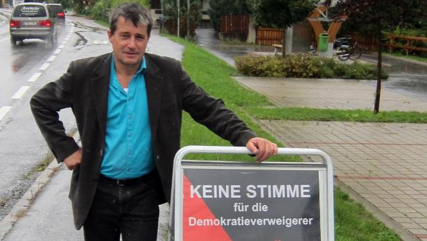 Ein Mann steht neben einem Schild mit der Aufschrift „Keine Stimme für die Demokratieverweigerer“.