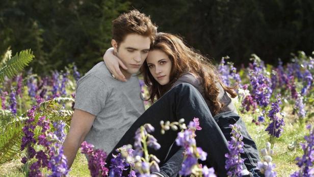 Robert Pattinson und Kristen Stewart sitzen in einem Blumenfeld.