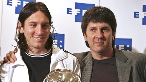 Lionel Messi posiert mit einem Mann und einer silbernen Fußballtrophäe.
