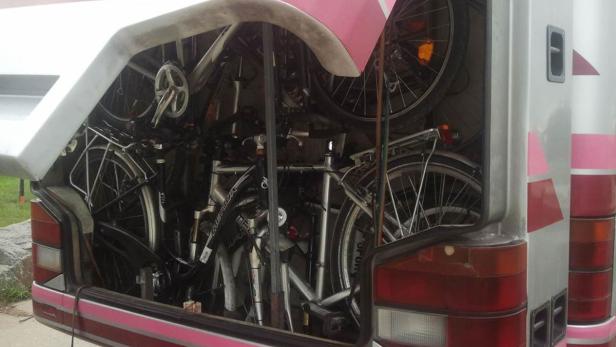 Mehrere Fahrräder sind im Heckstauraum eines silbernen Busses verstaut.