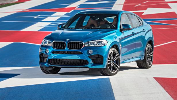Ein blauer BMW X6 M steht auf einer rot, weiß und blau gestreiften Fläche.