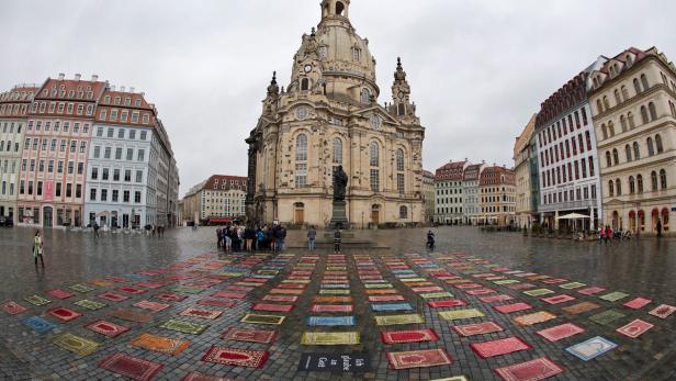 Die Frauenkirche in Dresden mit ausgelegten Gebetsteppichen auf dem Platz.