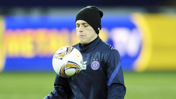 Ein Fußballspieler mit Mütze balanciert einen Ball vor der Brust.