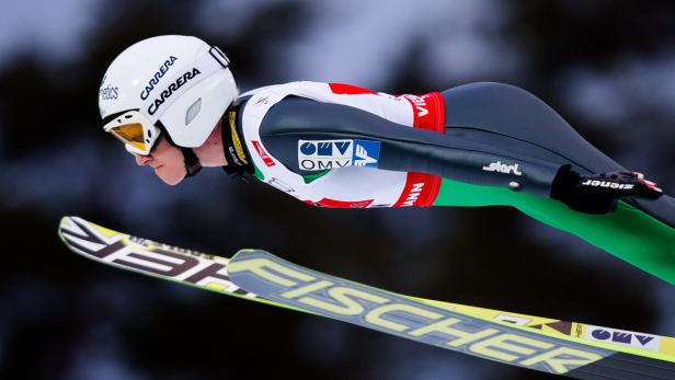 Ein Skispringer in der Luft mit Skiern der Marke Fischer.