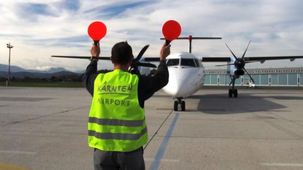 Ein Flugzeug wird von einem Mitarbeiter des Kärnten Airport eingewiesen.