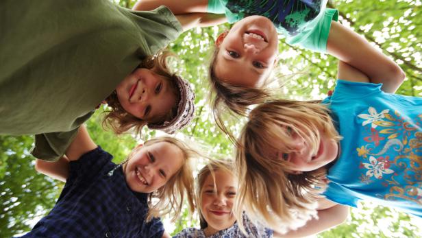 Fünf lächelnde Mädchen schauen von oben in die Kamera.