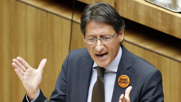 Ein Mann mit Brille gestikuliert und trägt einen Button mit der Aufschrift „Genug gezahlt!".