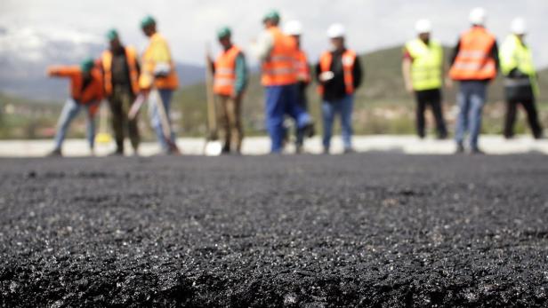 Workers spread asphalt on a highway, the first of its kind in Kosovo, being constructed in Vrmica April 15, 2011. The project, which started in April 2010, will link Kosovo with Albania in the west and Serbia in the east and could create up to 10,000 new jobs. The Bechtel-Enka consortium, made up of the San Francisco-based Bechtel International Inc. and Istanbul-based Enka, has already built a 65 km section of a highway in northern Albania. This highway will link up with that stretch. REUTERS/Hazir Reka (KOSOVO - Tags: SOCIETY TRANSPORT)
