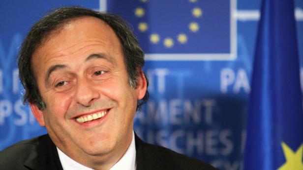 Michel Platini lächelt vor einer Europafahne.