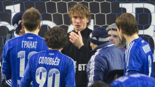 Ein Fußballtrainer bespricht sich mit seiner Mannschaft am Spielfeldrand.