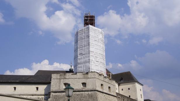 Ein Turm einer Burg ist mit Baugerüsten und Planen verhüllt.