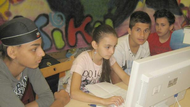 Eine Gruppe von Jugendlichen sitzt vor einem Computer.