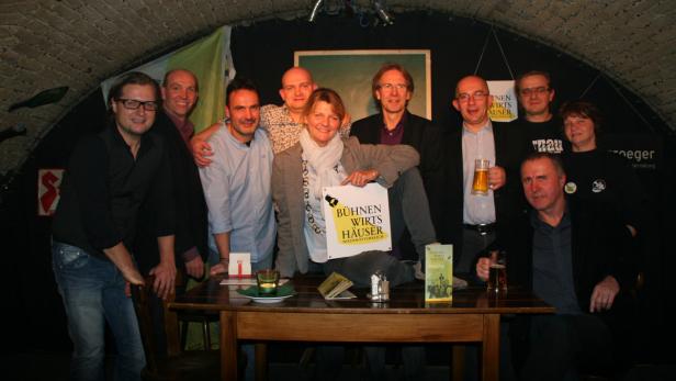 Eine Gruppe von Menschen posiert für ein Foto mit einem Schild „Bühnen Wirts Häuser Niederösterreich“.