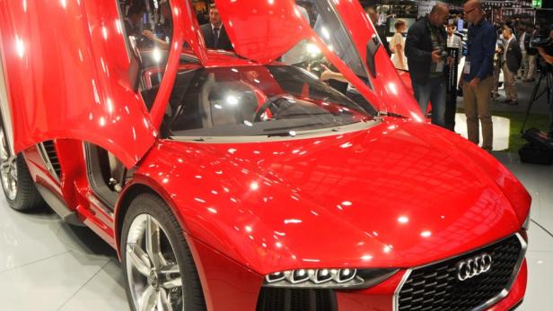 Ein roter Audi-Sportwagen mit geöffneten Flügeltüren steht auf einer Ausstellung.