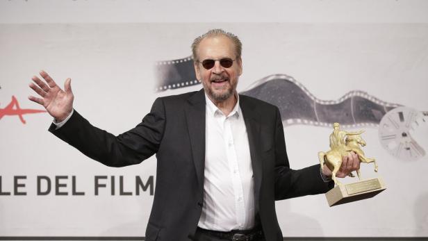 Paul Verhoeven mit Sonnenbrille und einem Preis in der Hand.