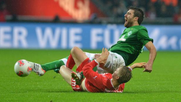 Zwei Fußballspieler kämpfen auf dem Rasen um den Ball.