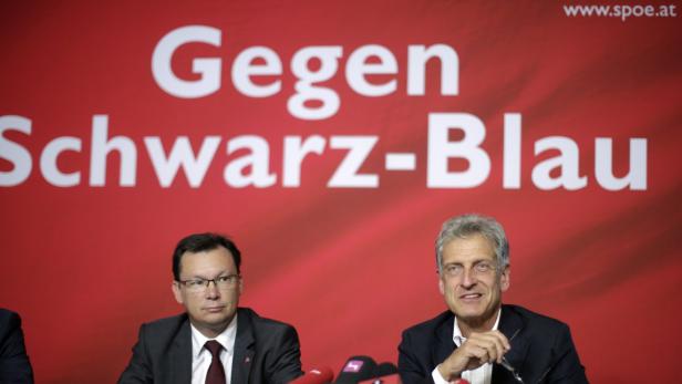 Zwei Männer sitzen vor einem roten Hintergrund mit der Aufschrift „Gegen Schwarz-Blau“.