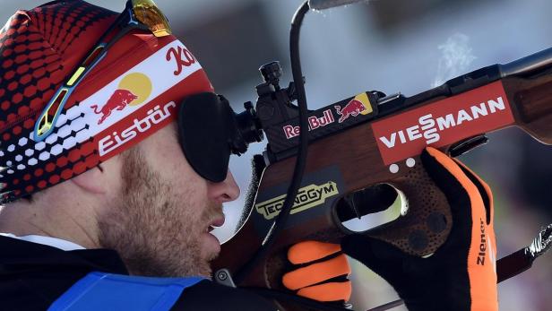 Ein Biathlet zielt mit einem Gewehr auf ein Ziel.
