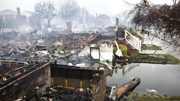 Die Überreste eines durch ein Feuer zerstörten Hauses stehen unter Wasser.