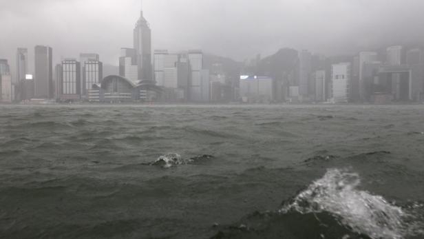 Die Skyline von Hongkong ist im Dunst zu sehen, aufgenommen vom unruhigen Wasser aus.