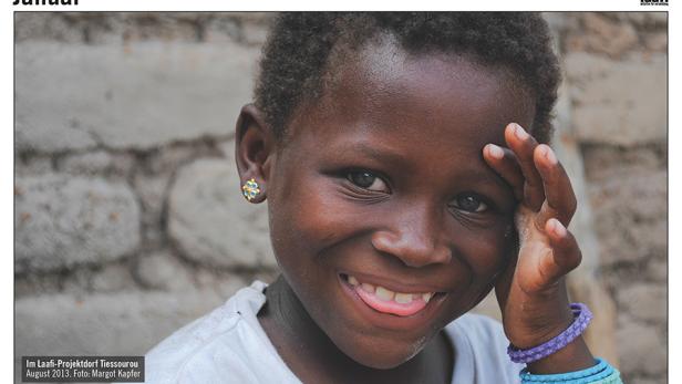 Ein lächelndes afrikanisches Kind mit Ohrring und Armbändern streckt die Zunge heraus.