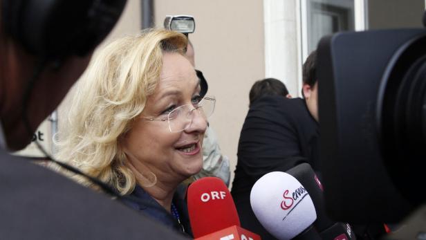 Eine Frau mit blonden Haaren spricht in mehrere Mikrofone.