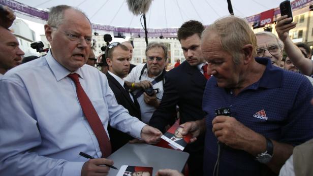 Peer Steinbrueck (L) of the Social Democratic Party (SPD), a challenger of German Chancellor Angela Merkel, signs autographs following an election campaign rally in the western German city of Essen September 5, 2013. Steinbrueck is trying to beat Merkel who is running for a third term in a parliamentary election on September 22. REUTERS/Wolfgang Rattay (GERMANY - Tags: POLITICS ELECTIONS)