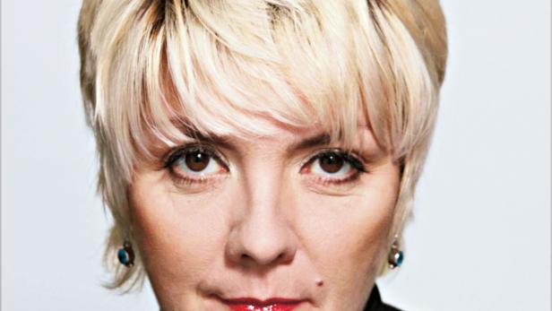 Porträt einer Frau mit blonden, kurz geschnittenen Haaren und rotem Lippenstift.