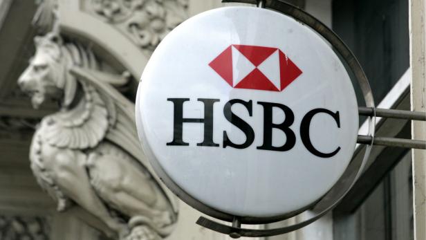 Ein Schild mit dem HSBC-Logo vor einem Gebäude mit einer Löwenstatue.