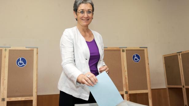 Eine Frau wirft einen blauen Stimmzettel in eine Wahlurne.