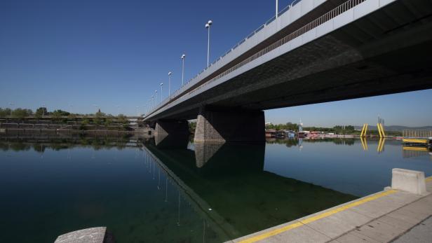 Eine Brücke überspannt einen ruhigen Fluss unter blauem Himmel.