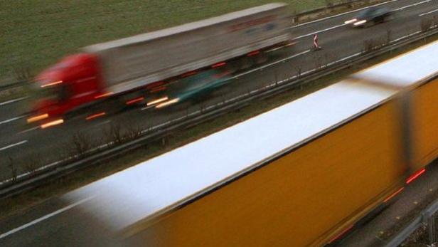 Mehrere Lastwagen und Autos fahren auf einer Autobahn.