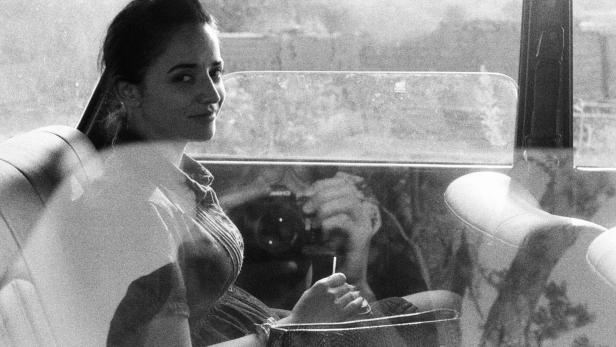 Eine Frau sitzt in einem Auto und blickt über die Schulter.