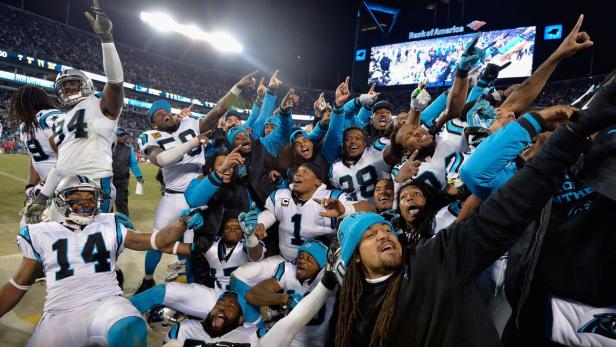 Eine Gruppe Footballspieler der Carolina Panthers feiert auf dem Spielfeld.