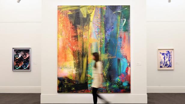 Eine Frau geht an einem großen, abstrakten Gemälde in einer Kunstgalerie vorbei.