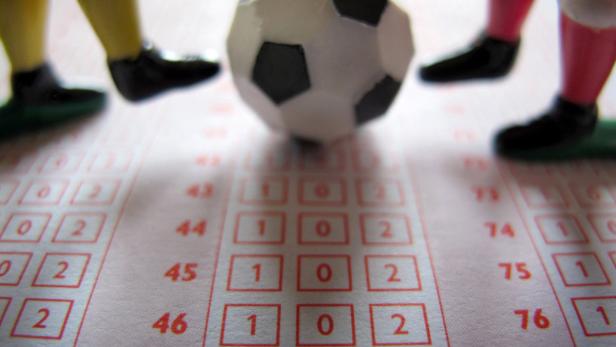 Ein Spiel mit einem Fußball und kleinen Figuren auf einem Tippschein.