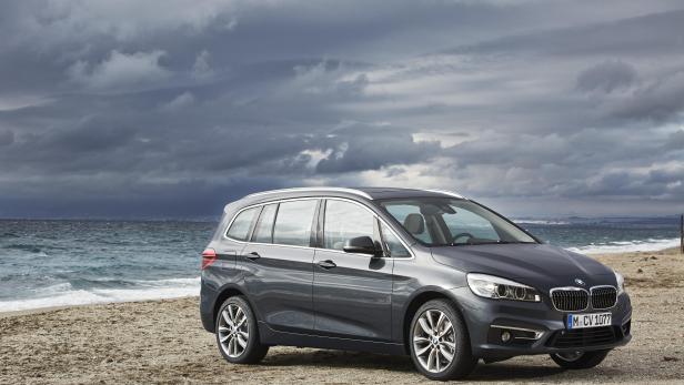 Ein grauer BMW 2er Active Tourer steht am Strand vor einem bewölkten Himmel.