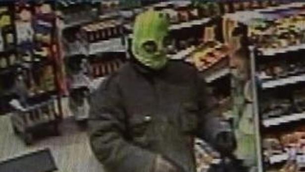 Eine Person mit einer grünen Maske steht in einem Geschäft.