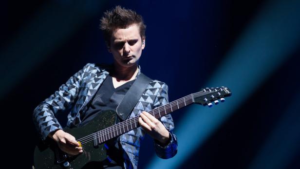 Matt Bellamy von Muse spielt Gitarre auf der Bühne.